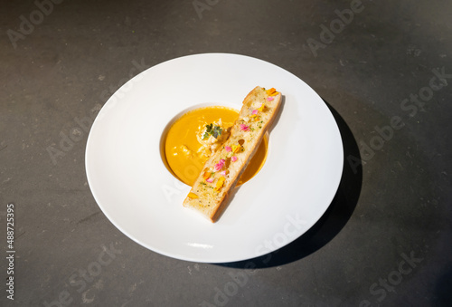 Topview Flat Lay of Garlic Bread with Creamy TomYamKung Soup on white dish in studio light, decorated with flower petal on it. Clipping Paths. photo