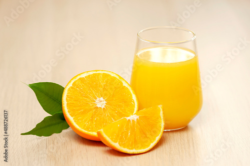 Orange juice in a glass with orange slices and a green leaf