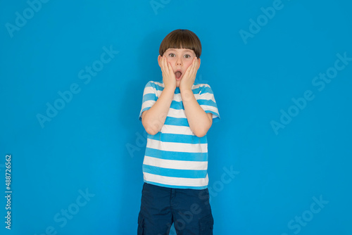 Boy surprised with open mouth on a blue background. photo