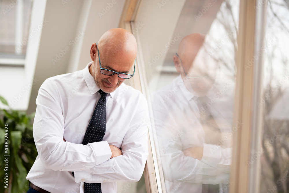 Thinking businessman portrait while standing at the window