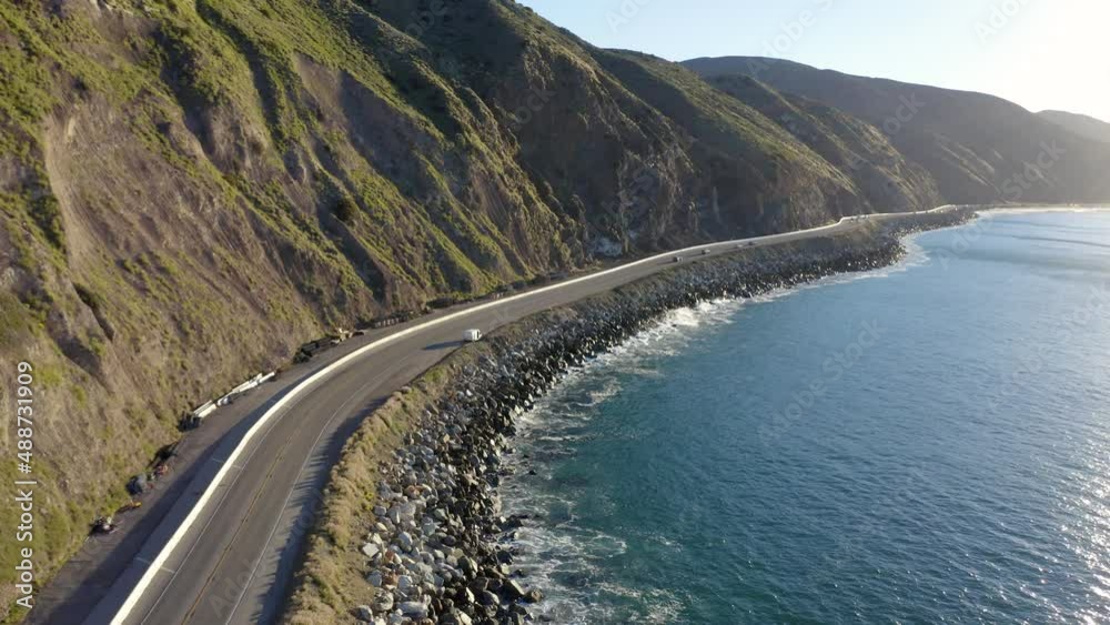 On the open road, ready for a road trip. Aerial view of a road running between a mountain and the ocean. Top view of a coastline road and beach resorts at sunset. Malibu Beach coastline in California On the open road, ready for a road trip. Aerial view of a road running between a mountain and the ocean. Top view of a coastline road and beach resorts at sunset. Malibu Beach coastline in California