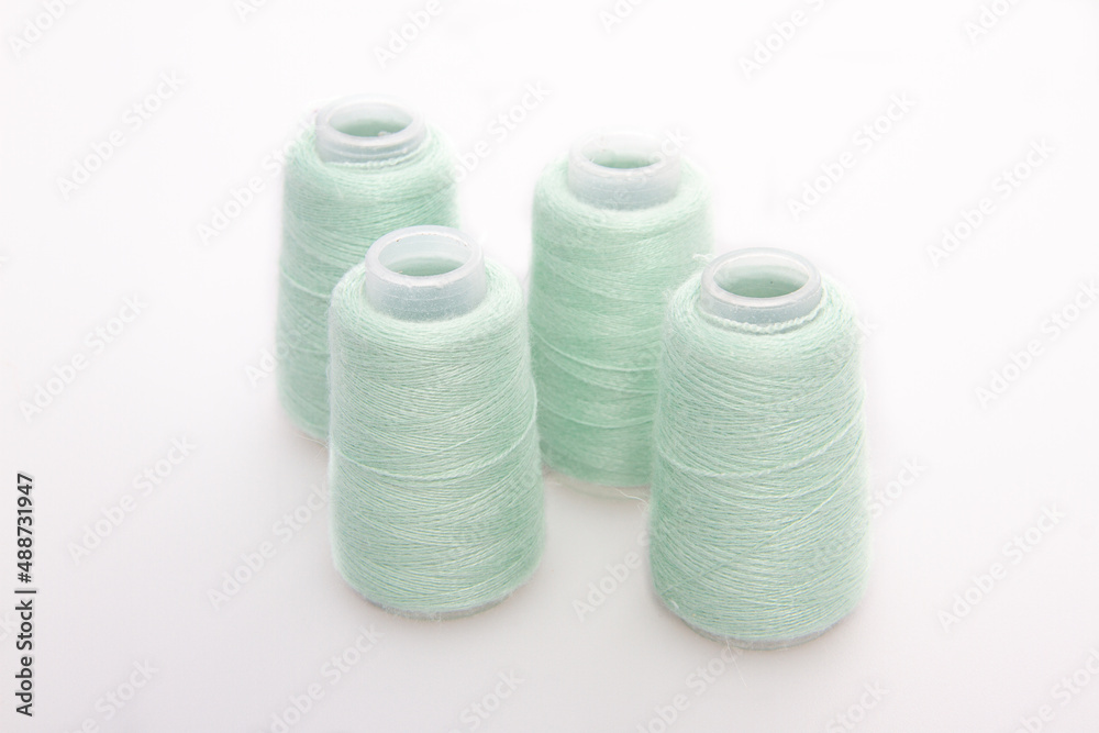 Green spool of thread isolated on white background. Skein of woolen threads. Yarn for knitting. Materials for sewing machine. Coil. Green spool of thread isolated on white background. Skein of woolen threads. Yarn for knitting. Materials for sewing machine. Coil.