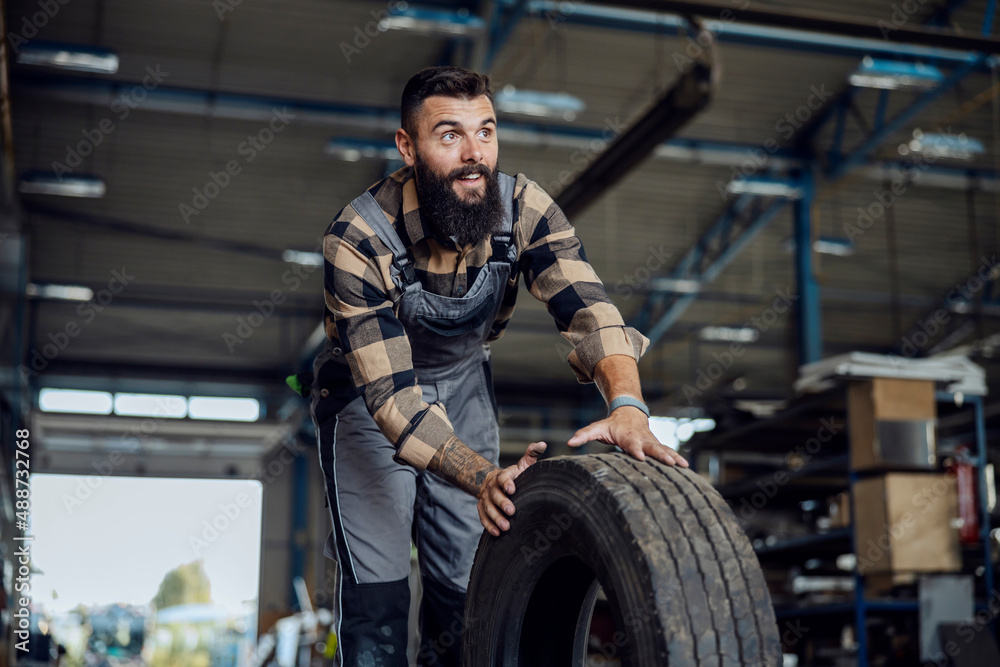 Auto-mechanic in a workshop with tire. Auto-mechanic in a workshop with tire.