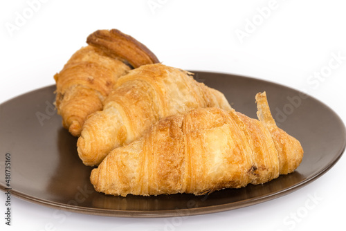 Small croissants on brown dish, close-up in selective focus
