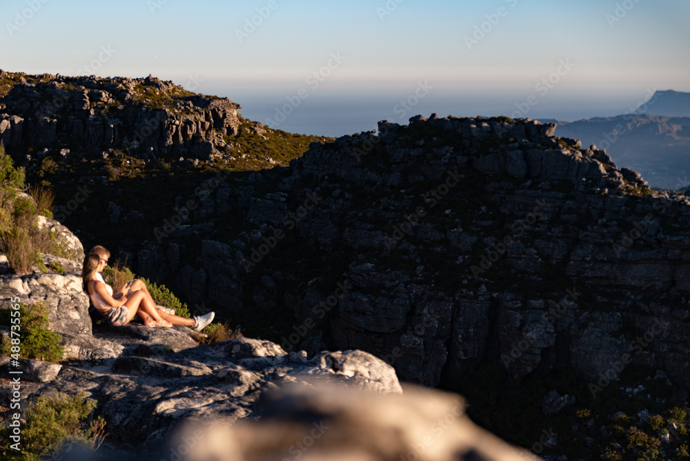 Couple enjoying romantic sunset on a mountain. Date on a mountain top at sunset. Hikers watching the sun over the mountain ridge. 