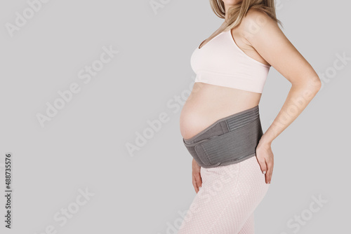 Pregnant woman belly in prenatal pregnancy maternity belt. Orthopedic abdominal support waist, back, abdomen band. Belly brace or band for pregnancy. Horizontal web banner. Torso of pregnant model. photo