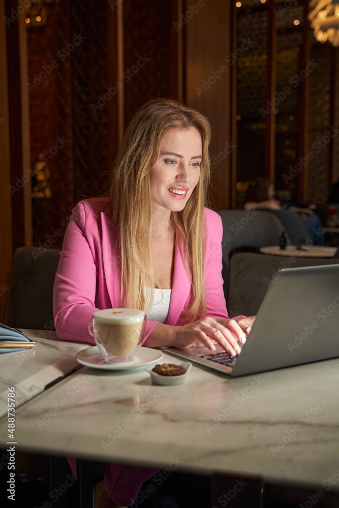 Gladsome young lady working on laptop from cozy coffee place Gladsome young lady working on laptop from cozy coffee place