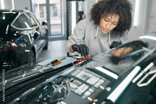 Quadro su tela Concentrated car mechanic affixing automotive equipment to windscreen