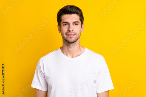 Photo of charming confident positive man look camera wear white t-shirt isolated yellow color background