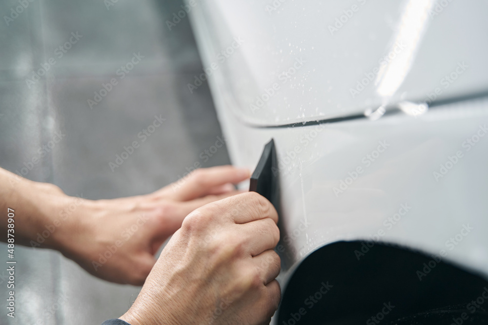 Worker hands polishing exterior surface of auto body panel