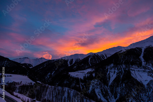 Winter scenery while sunrise in the European Alps, Graubuenden, Switzerland, with snow-covered mountains, clouds, and sky