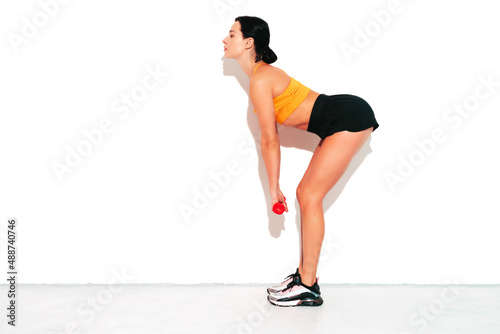 Fitness confident woman in sports clothing. Sexy young beautiful model with perfect body. Female isolated on white wall in studio. Stretching out before training.Making exercises with dumbbells