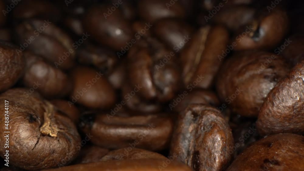 Backward glide from extreme close over a pile of roasted coffee beans, 4k ultra macro