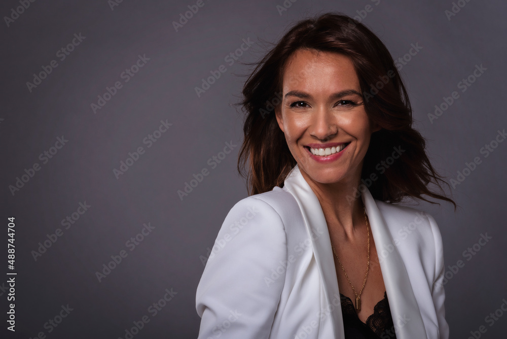 Beautiful brown haired woman studio shot while sitting at isolated background