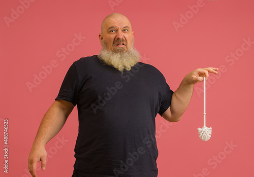 bearded man holding smelly toilet brush on pink background
