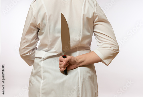 woman holding a knife behind her back on a white background, close-up