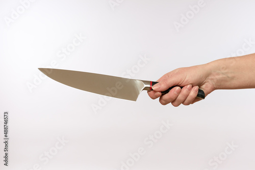 female hand holding a sharp steel knife on a white background, close-up