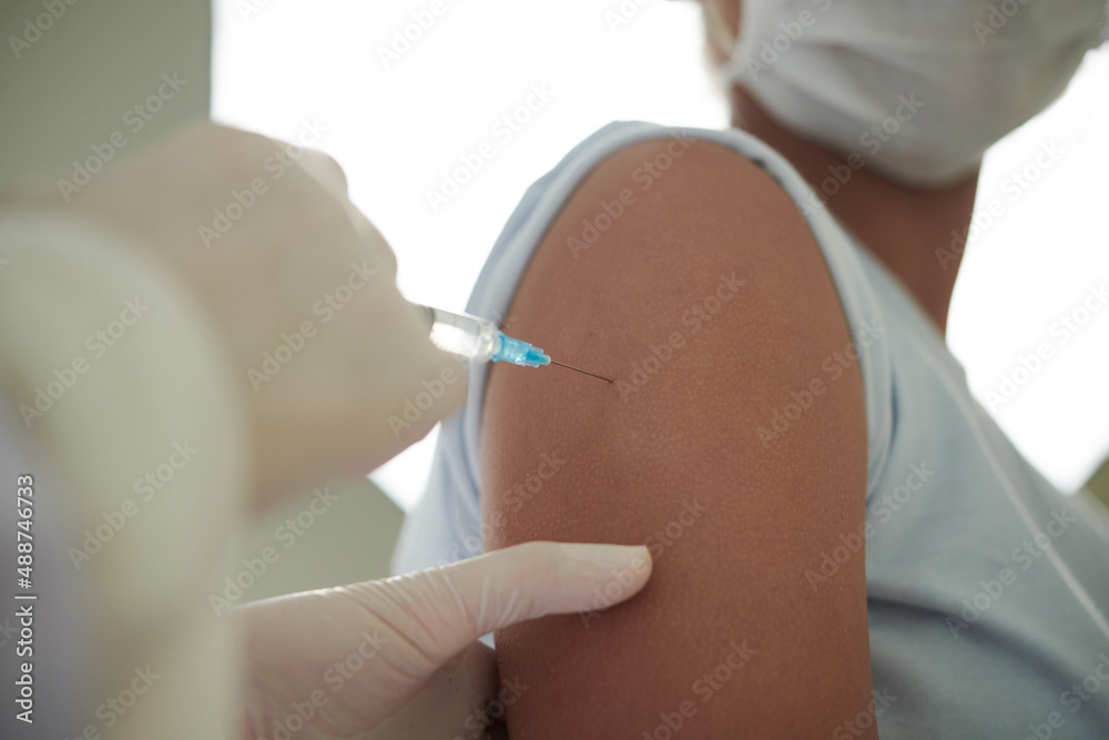 Close-up of teenager getting injection from covid in her arm at hospital Close-up of teenager getting injection from covid in her arm at hospital