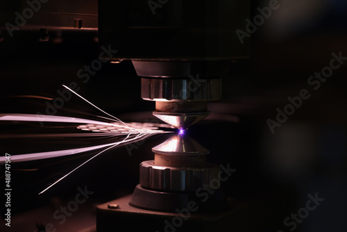 Laser machine cutting sheet of metal with bright sparks closeup