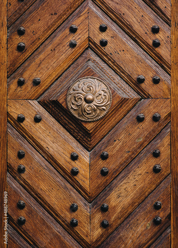 Old wooden brown door with diamond-shaped pattern in the rays of daylight. Vintage background