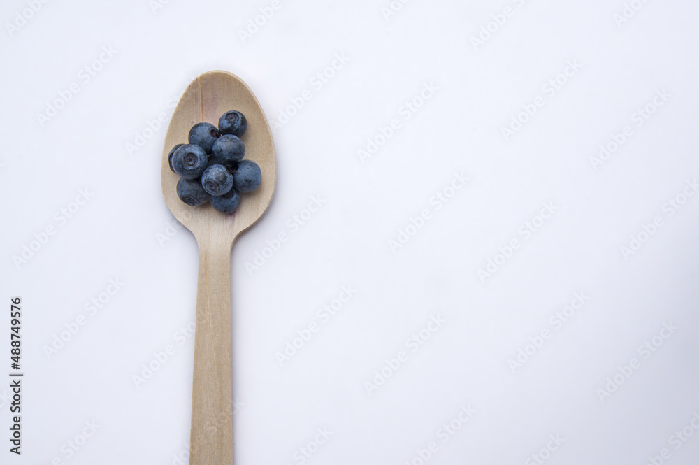Recycled spoon and juicy, fresh blueberries on color table Recycled spoon and juicy, fresh blueberries on color table