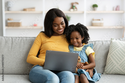 Digital Leisure. Happy Black Mother And Little Daughter Using Laptop At Home
