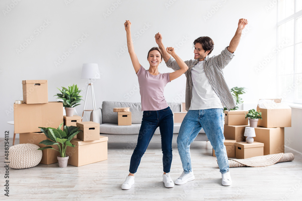 Happy glad millennial european lady and guy in casual dancing, enjoy relocation in room Happy glad millennial european lady and guy in casual dancing, enjoy relocation in room