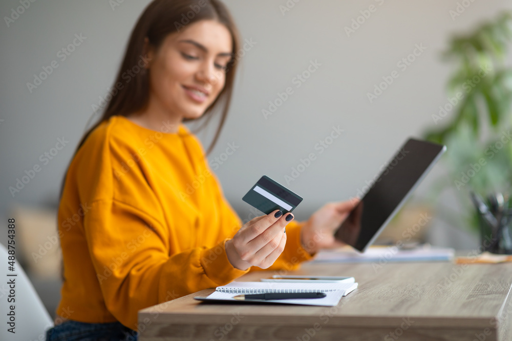Online shopping, remote banking. Young lady with credit card and tablet buying on internet, using new web store app Online shopping, remote banking. Young lady with credit card and tablet buying on internet, using new web store app