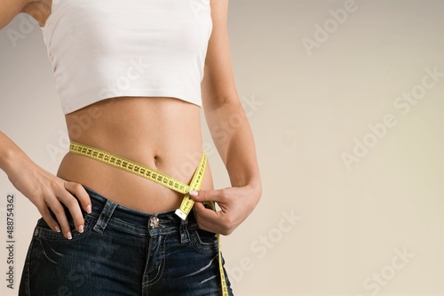 Fit Sporty girl with measuring tape at hips. Perfect woman body. Diet or health care concept. © BillionPhotos.com