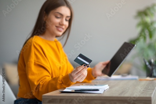 Online shopping, remote banking. Young lady with credit card and tablet buying on internet, using new web store app