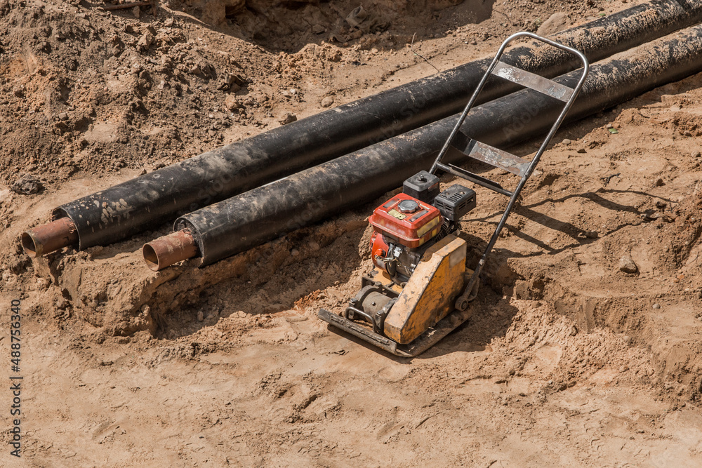 Repair of the water line of the heating main pipe in the ground trench pipeline at the construction site work industry, soil compaction pneumatic rammer