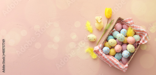Basket with painted Easter eggs  bunny and tulip flower on color background with space for text