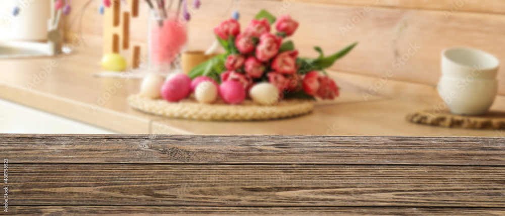 Empty wooden table in kitchen decorated for Easter celebration Empty wooden table in kitchen decorated for Easter celebration