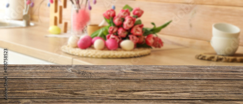 Empty wooden table in kitchen decorated for Easter celebration