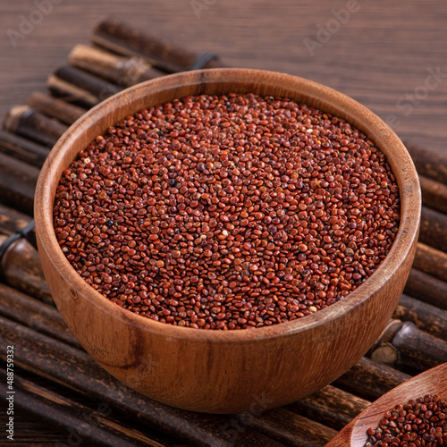 Organic red quinoa in a bowl on wooden table background.