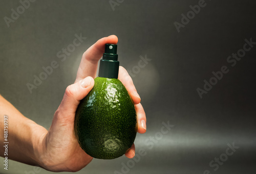 hand holding avocado with cream dispenser - natural cosmetics concept