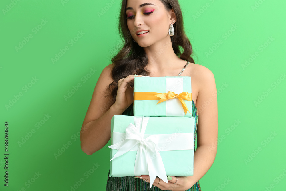 Young woman with creative makeup holding stack of gift boxes on green background. International Women's Day Young woman with creative makeup holding stack of gift boxes on green background. International Women's Day