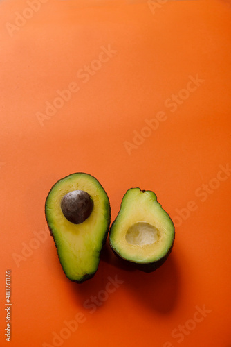 Two simple slices of avocado on bright orange background, copy space