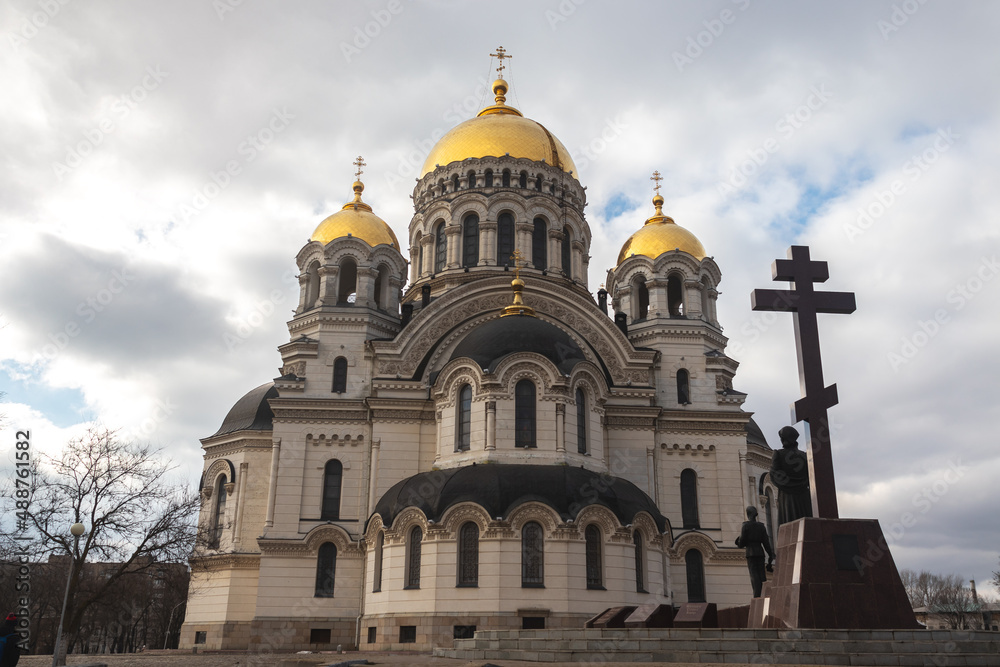 Orthodox church with golden domes and crosses against a clear blue sky with clouds.l