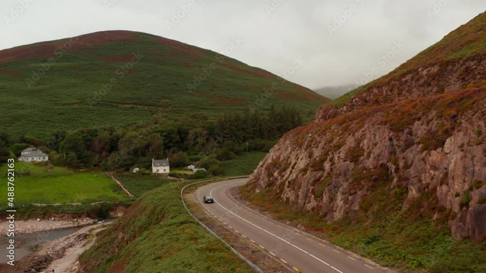 Tracking of car passing through curves around steep rock slope. Road leading in countryside. Ireland Tracking of car passing through curves around steep rock slope. Road leading in countryside. Ireland