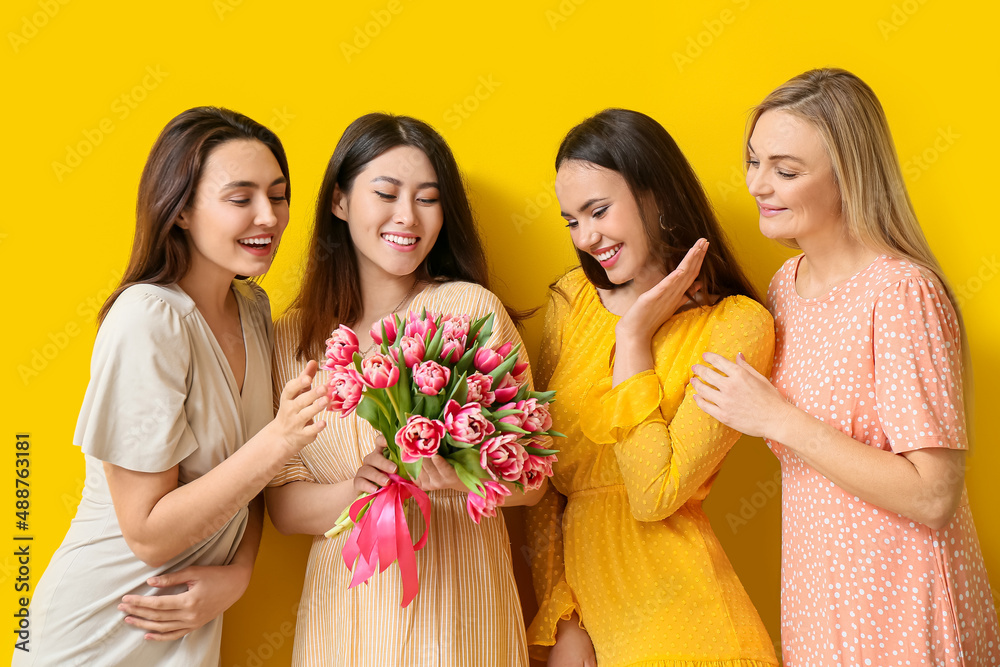 Beautiful women with bouquet of flowers on yellow background. International Women's Day celebration Beautiful women with bouquet of flowers on yellow background. International Women's Day celebration