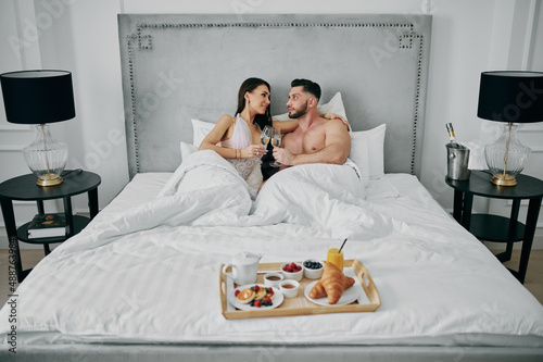 a woman and a man in a bathrobe with breakfast in bed