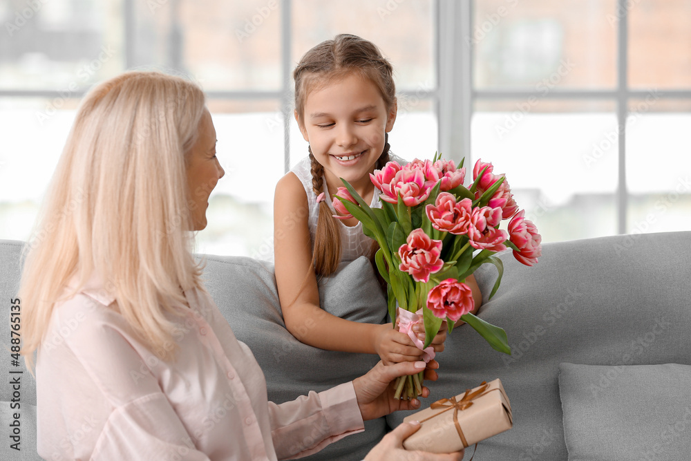 Little girl greeting her grandmother with tulips at home on International Women's Day Little girl greeting her grandmother with tulips at home on International Women's Day