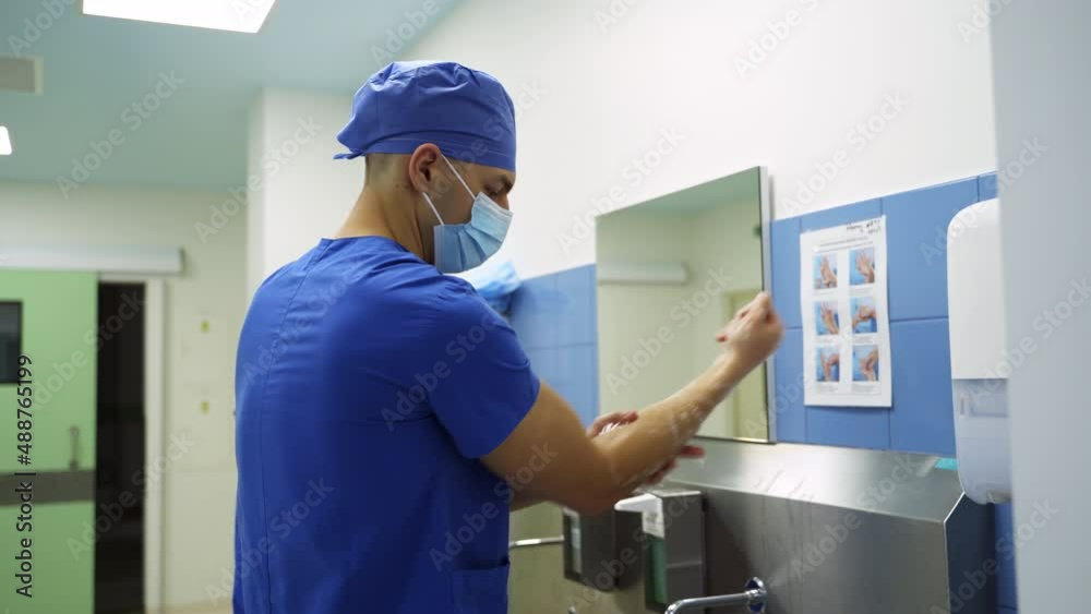 Surgeon doctors preparing carefully for operation. Male doctor washing hands with soap up to his elbows. Side view. Surgeon doctors preparing carefully for operation. Male doctor washing hands with soap up to his elbows. Side view.