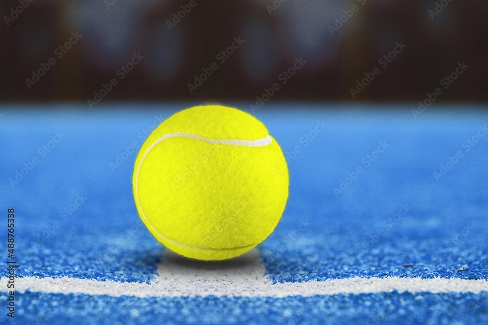 Padel classic yellow ball on a blue court