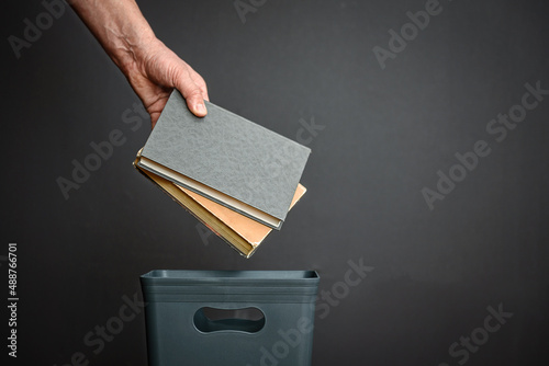 Papier peint Hand Throws Old Books into Trash Literary Discard Moment