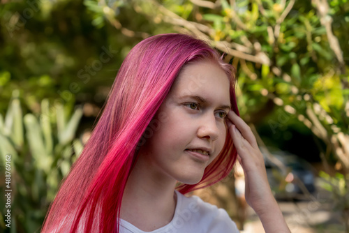 Cute teenage girl with bright raspberry pink ombre long colored hair. Generation Z styles and trends.