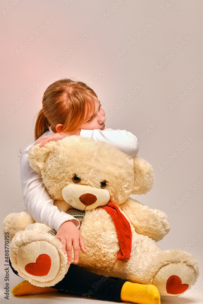 Girl hugging a toy bear. The child plays with a toy at home. Strong friendship .