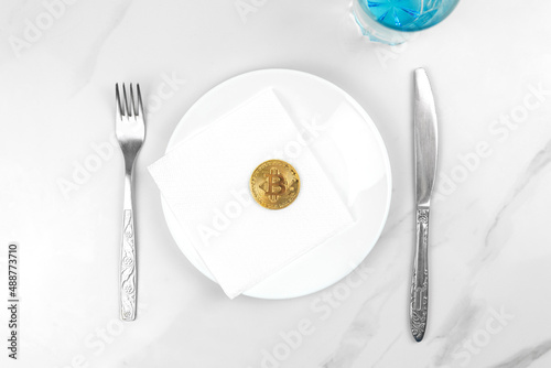 Bitcoin gold coin concept. Cryptocurrency mixed media image. Served bitcoin on a white plate. Marble background