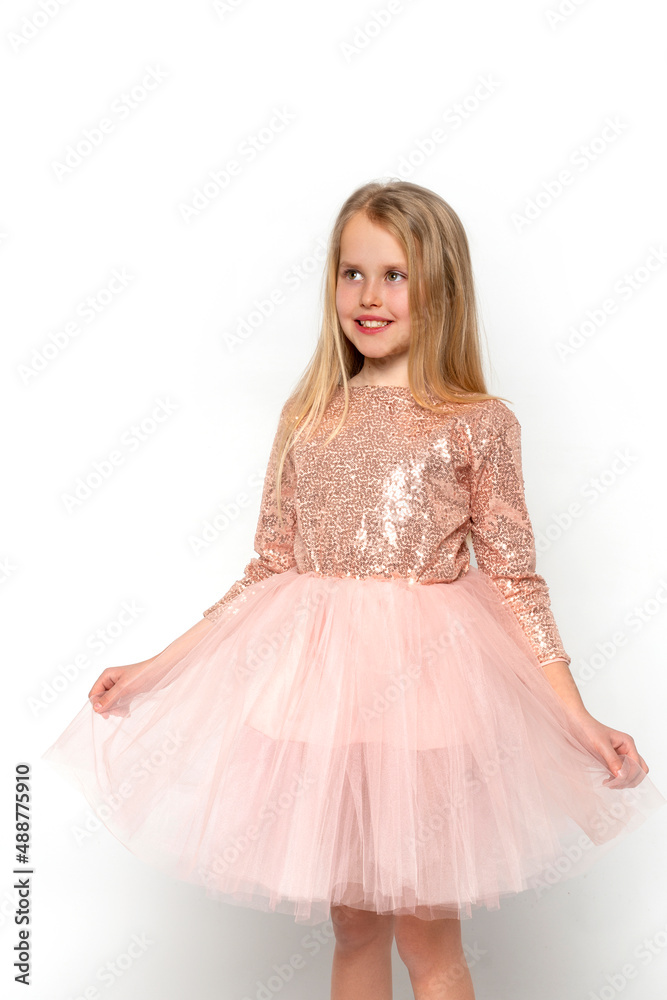 Studio shot of attractive little girl wearing pink ball gown and crown posing against white background in studio Studio shot of attractive little girl wearing pink ball gown and crown posing against white background in studio